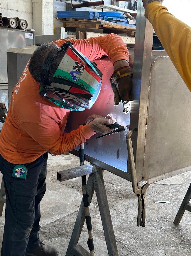 Trabajador de ASLAN INDUSTRIAL soldando una pieza de acero inoxidable en el taller.